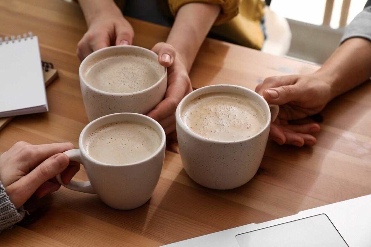 Three freshly-made lattes on a wooden office table