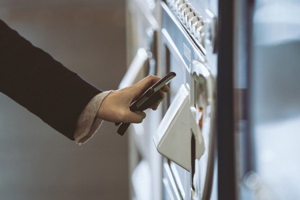 Employee using cellphone to pay for vending machine purchase