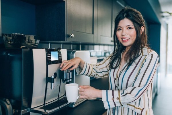 A woman using a coffee dispenser to get fresh coffee